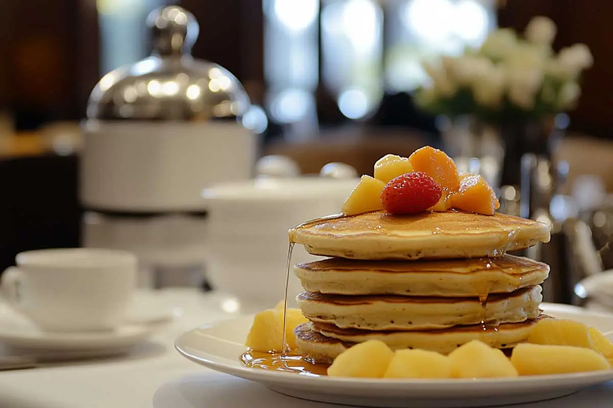 Stack of sourdough discard pancakes with syrup, butter, and fresh fruit on a cozy breakfast table