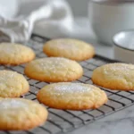 Golden sourdough discard sugar cookies cooling on a rack with sugar and a cup of coffee.